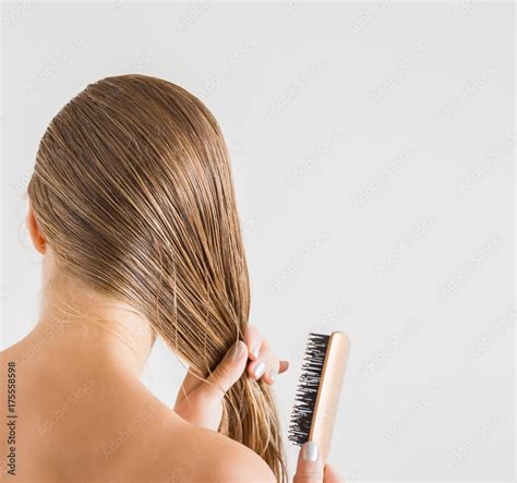 Woman With Comb Brushing Her Wet Blonde Hair After Shower On The Gray