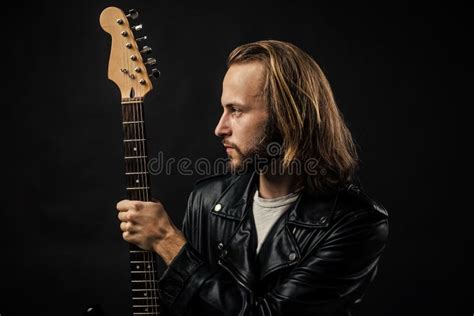 Bearded Rock Musician Holding Electric Guitar Neck In Leather Jacket