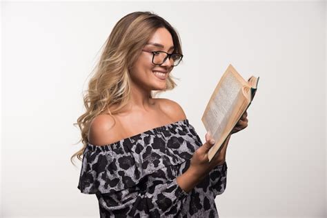 Mujer Joven Con Gafas Leyendo Un Libro Sobre La Pared Blanca Foto Gratis