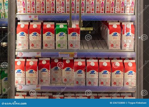 A Single Green Milk Carton In Between Severan Red Milk Cartons