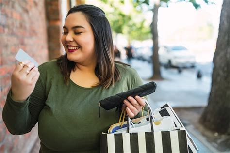 Retrato de jovem plus size mulher segurando um cartão de crédito e