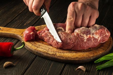 Premium Photo The Chef Cuts Raw Beef Meat On A Cutting Board Before