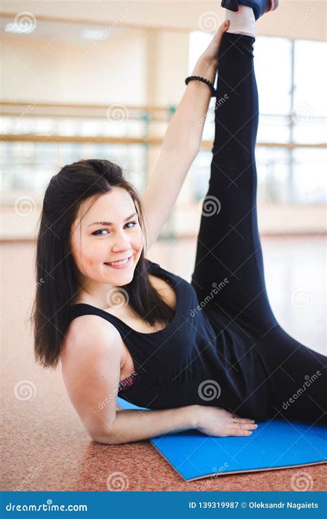 La Mujer Que Hace Estirar Ejercita En El Piso En El Gimnasio Imagen De