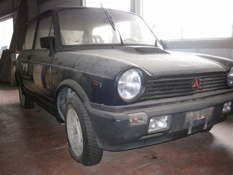 An Old Black Van Parked In A Garage Next To A Window With The Sun