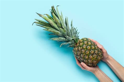 Premium Photo Female Hands Hold A Whole Ripe Pineapple On A Blue