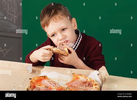 Los niños comen pizza italiana en el café El chico de la escuela está