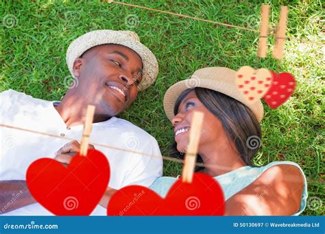 Composite Image Of Happy Couple Lying In Garden Together On The Grass