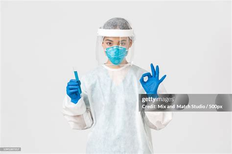 Portrait Of Female Doctor Wearing Surgical Mask While Standing Against