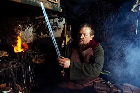 Premium Photo | Viking blacksmith forges weapons in the old vintage forge.