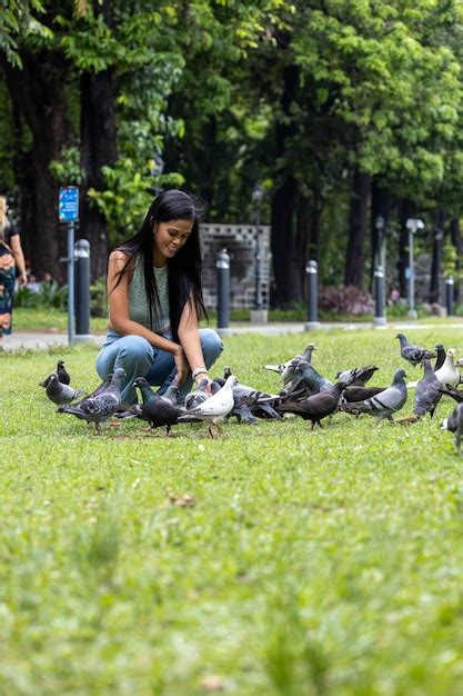 Premium Photo | Girl feeding pigeons in the park