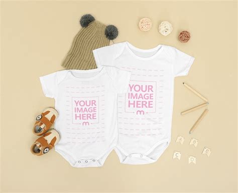 Two Size Baby Onesie Mockup Laid Over A Brown Background Mediamodifier