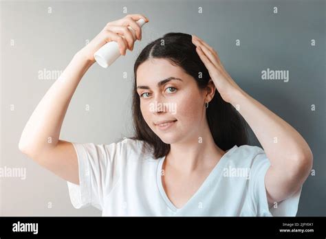 Une jeune belle femme vaporise des cosmétiques de soin sur ses cheveux