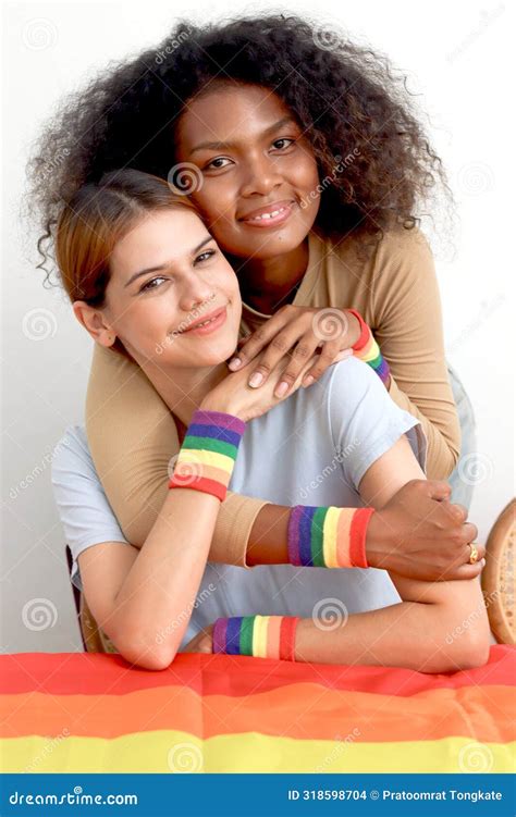 Happy Smiling Homosexual Lesbian Couple With Rainbow Flag Wristband Hugging Each Other