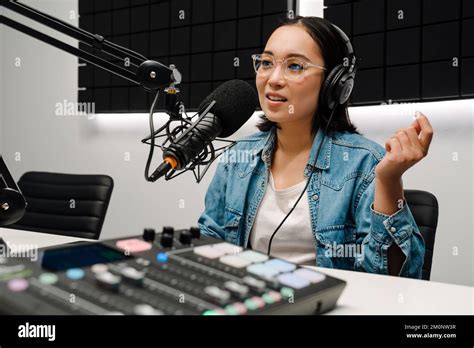 Beautiful Happy Young Female Radio Host Using Microphone And Headphones