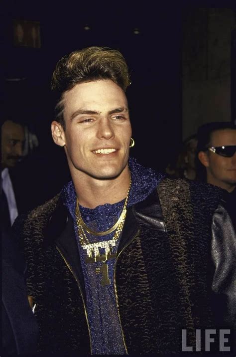 A Young Man Smiling At The Camera Wearing A Blue Shirt And Gold Chain