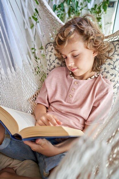 Niño con libro acostado en hamaca Foto Premium