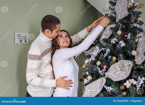 Couple Of Lovers Trim A Christmas Tree Together On The Eve Of The Christmas Holidays Stock Image