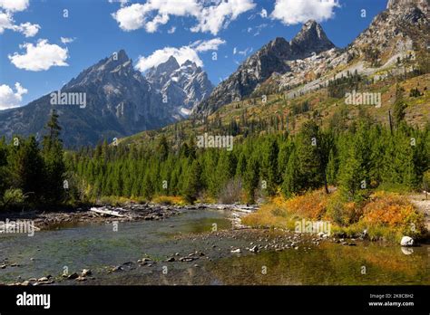 Fall colors lining the lakeshore and rising up the Teton Mountains as ...