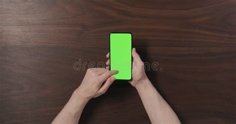 Top View Man Hands Hold Smartphone With Green Screen Over Black Walnut