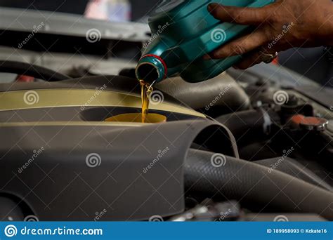 Car Mechanic Replacing And Pouring Fresh Oil Into Engine At Maintenance