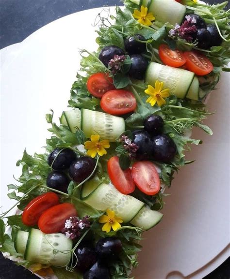 A White Plate Topped With Cucumbers Tomatoes And Black Olives On Top