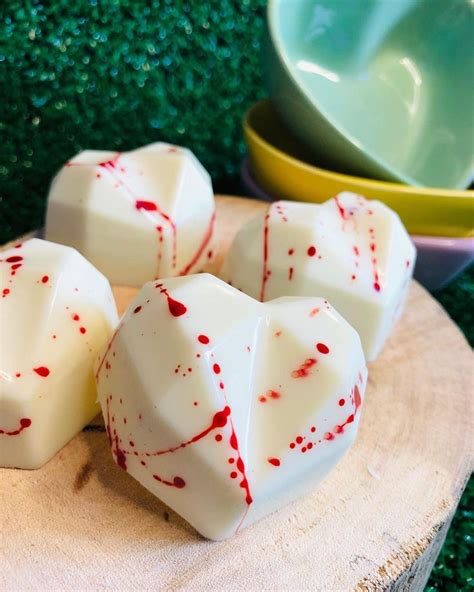 Four White Dices With Red Splatters On Them Sitting On A Wooden Board