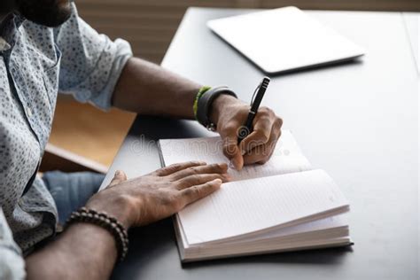 Focused Young Mixed Race Businessman Writing Notes In Paper Notebook