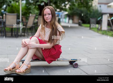 Cute Teen Mädchen sitzen auf einem Skateboard auf der Straße