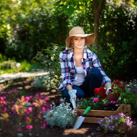 Tragender Strohhut Des Schönen Weiblichen Gärtners Der Blumen in Ihrem