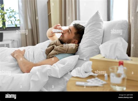 Sick Man With Nasal Spray Lying In Bed At Home Stock Photo Alamy