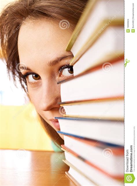 La Jeune Femme Regarde à L extérieur De Pour Des Piles Des Livres Photo