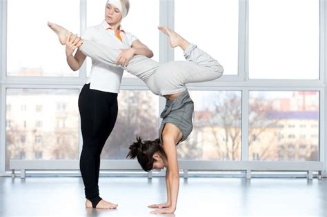 Free Photo Teacher Helping Student To Do Stag Handstand