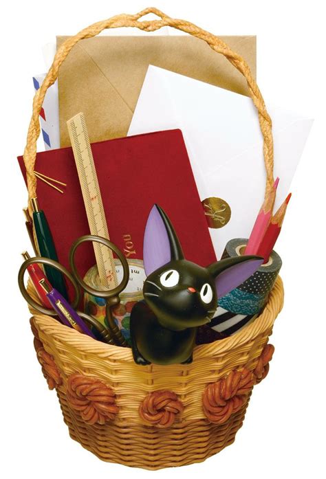 A Black Cat Figurine Sitting In A Basket Filled With Office Supplies